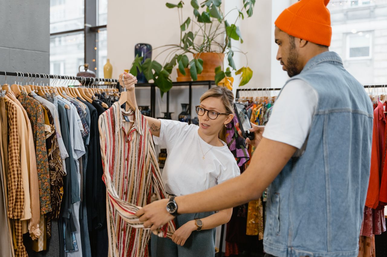 A woman helps a man choose a shirt in a modern clothing store.